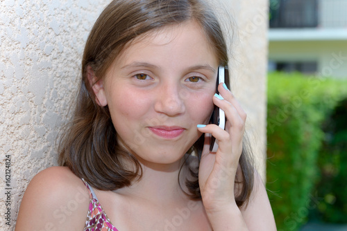 smiling pre teenager girl calling on smartphone, outdoor