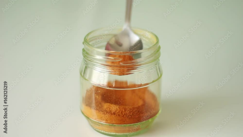 Taking curcuma from a glass can Taking curcuma from a glass can