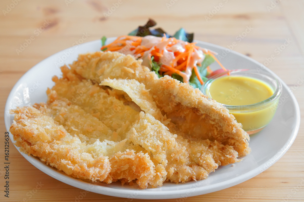 breaded pork cutlet delicious food with salad and sauce for lunch or breakfast and dinner on the white dish and the wood table at cafe or restaurant breaded pork cutlet delicious food with salad and sauce for lunch or breakfast and dinner on the white dish and the wood table at cafe or restaurant