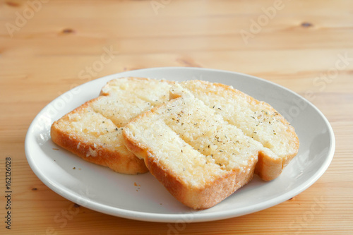 garlic butter bread and delicious dessert on white dish and wood table for breakfast or snack food in the morning at cafe or restaurant