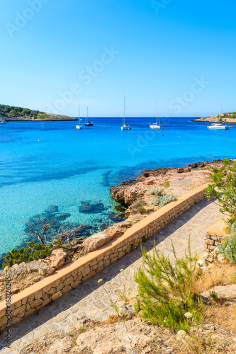 View of coastal promenade along blue sea in Cala Portinatx bay  Ibiza island  Spain