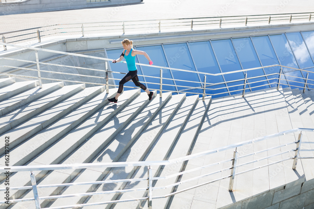 Full length shot of healthy young woman climbing up and running on stairs Full length shot of healthy young woman climbing up and running on stairs