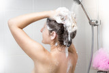 Woman washing head with shampoo in shower