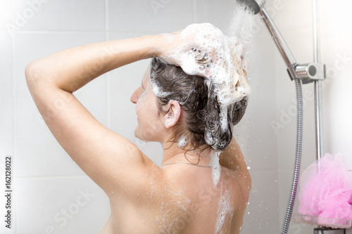 Woman washing head with shampoo in shower