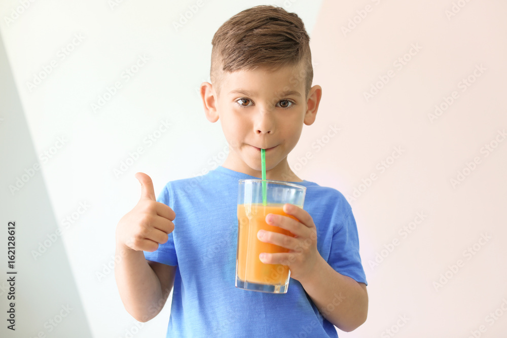 Cute little boy drinking juice on light color background Cute little boy drinking juice on light color background
