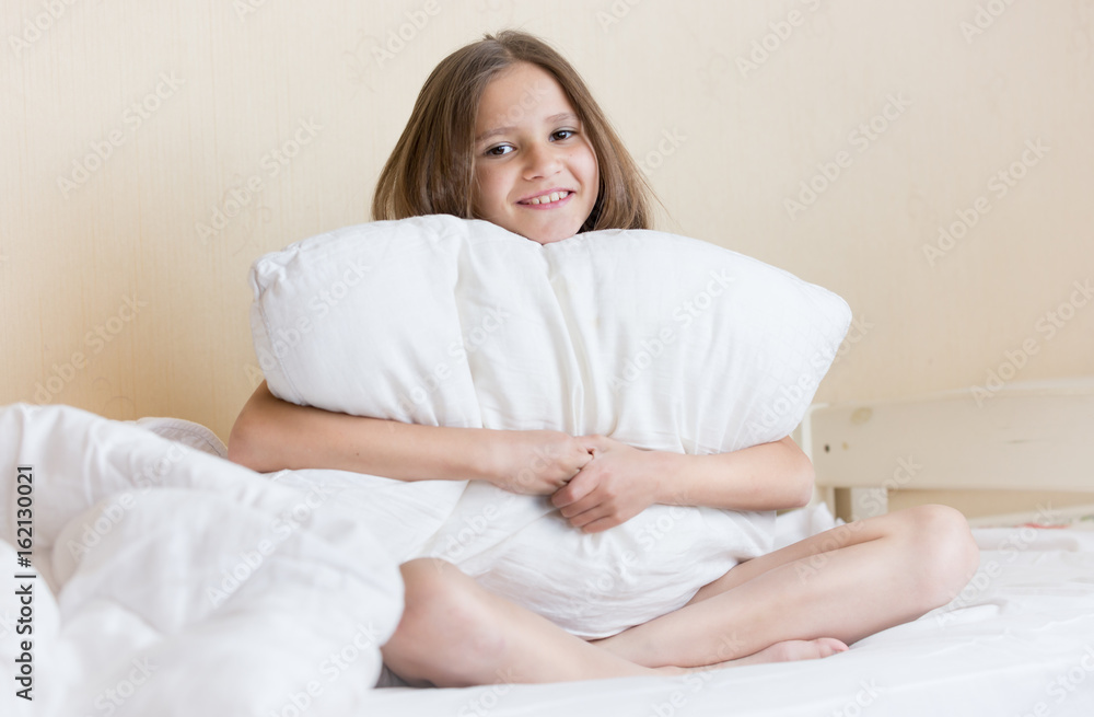 Portrait of beautiful brunette girl sitting on bed with white pillow Portrait of beautiful brunette girl sitting on bed with white pillow