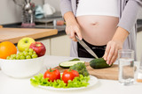 Closeup photo of pregnant woman making salad on kitchen