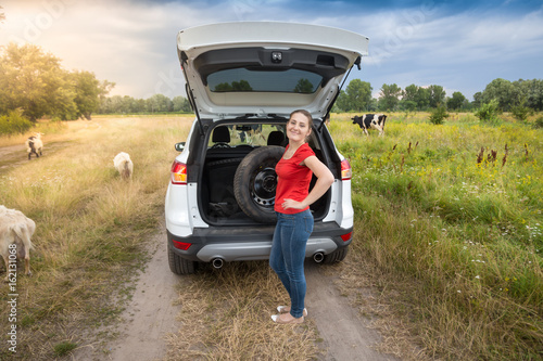 Young woman posing with spare wheel at broken car in the countryside © Кирилл Рыжов