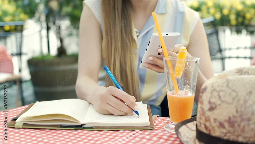 Girl browsing internet on smartphone and doing notes in notebook, steadycam shot
