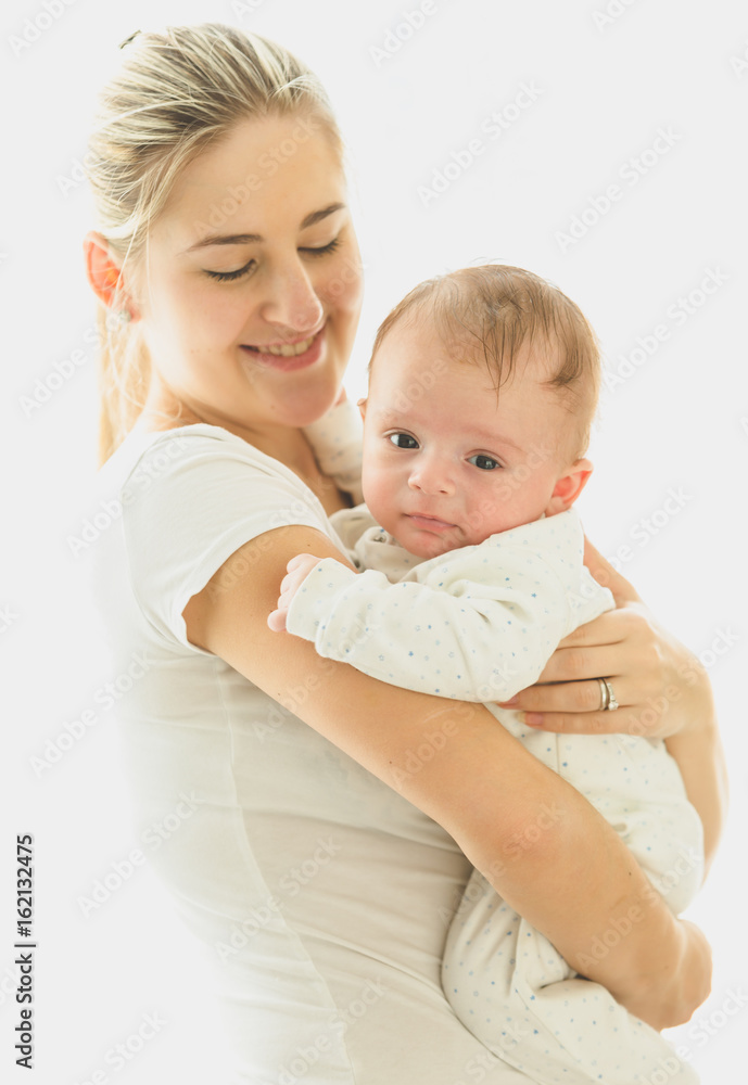 Smiling caring mother cuddling her 3 months old baby at big window at sunny day Smiling caring mother cuddling her 3 months old baby at big window at sunny day