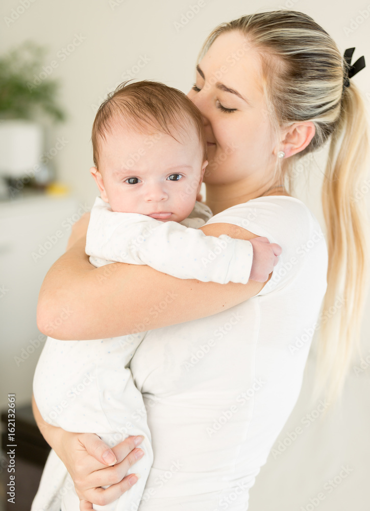 Young beautiful woman kissing her baby boy on hands Young beautiful woman kissing her baby boy on hands