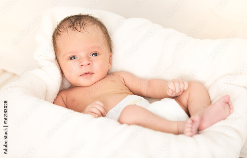 Smiling baby boy lying on soft beige blanket and cushion Smiling baby boy lying on soft beige blanket and cushion