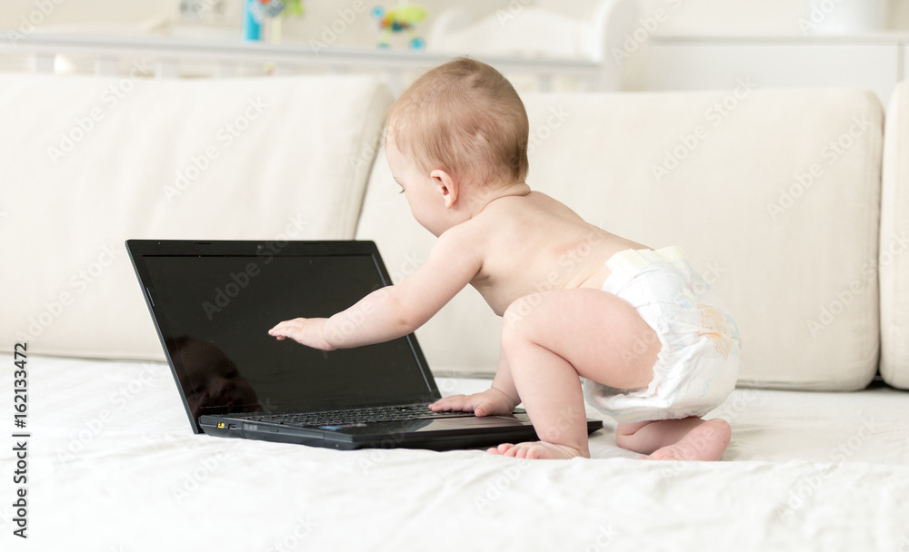 1 year old baby boy on bed using laptop 1 year old baby boy on bed using laptop