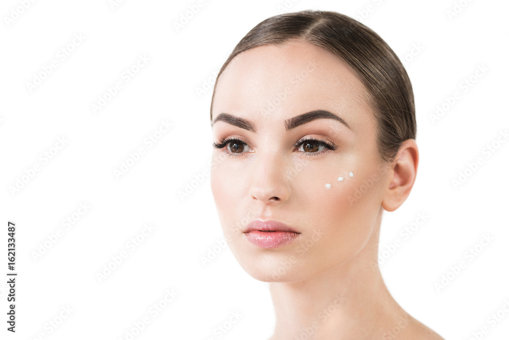 Serious beautiful girl using cosmetics for face skin