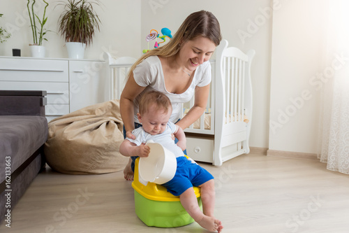 Foto Mother sitting her baby on chamber pot