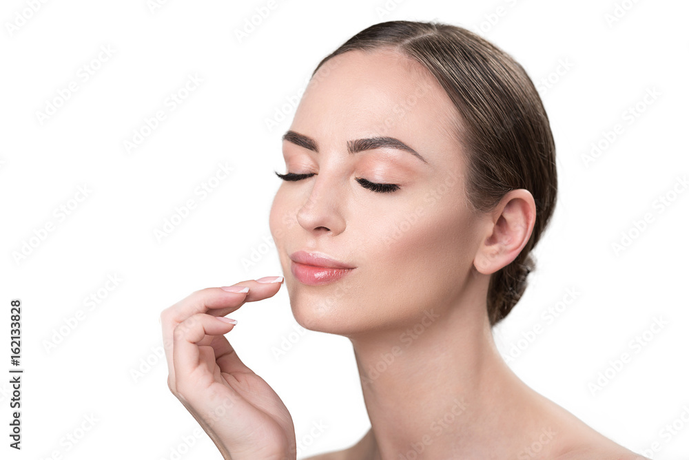 Joyful attractive girl feeling pleasure using facial cosmetics
