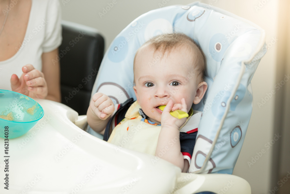 9 months baby boy with spoon sitting in highchair 9 months baby boy with spoon sitting in highchair