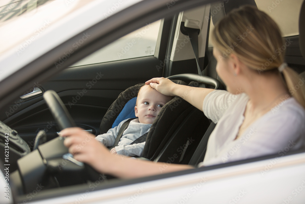 Young smiling woman posing in car with her baby boy Young smiling woman posing in car with her baby boy
