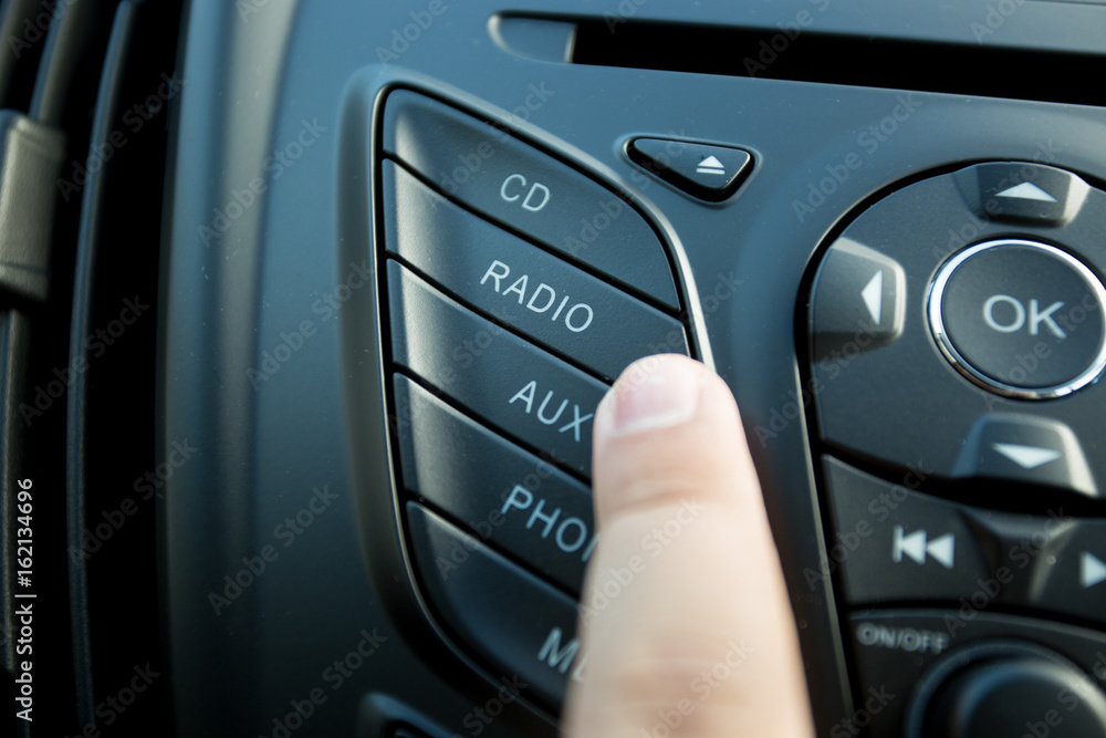 Closeup photo of driver pushing radio button on dashboard