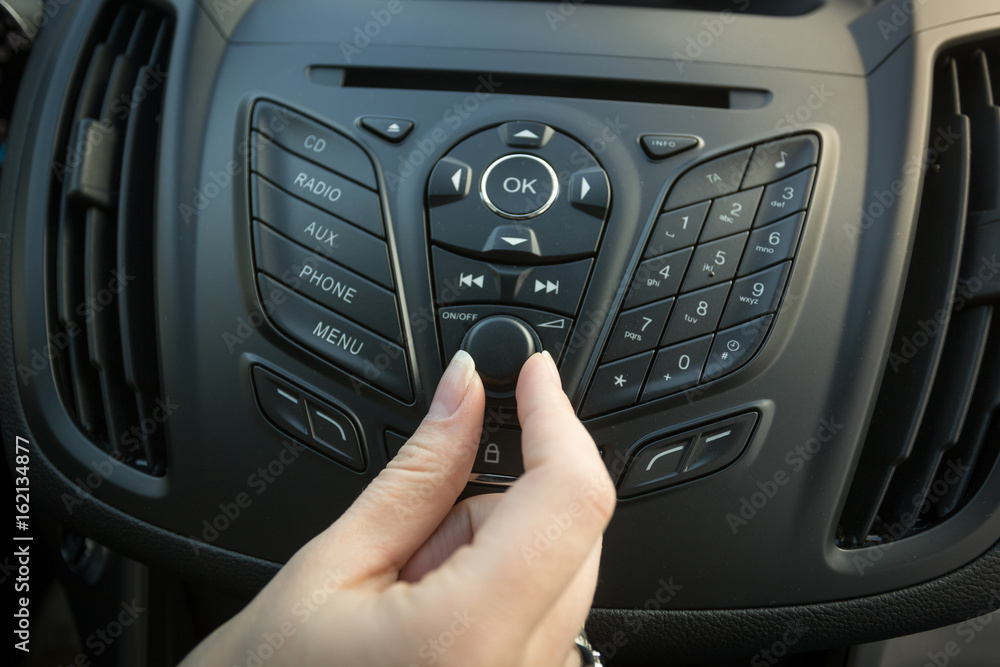 Closeup image of female driver adjusting car stereo system