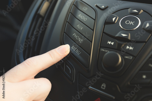 Female driver pressing phone control button on car dashboard