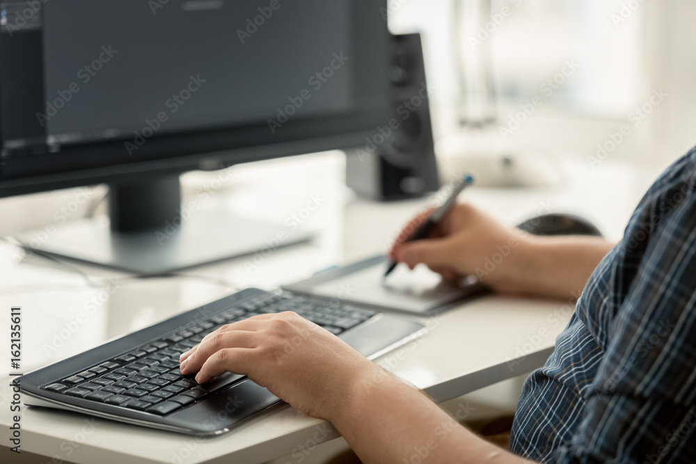 Toned photo of graphic designer using tablet and keyboard at work Toned photo of graphic designer using tablet and keyboard at work