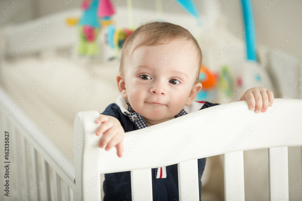 Portrait of 9 month old boy standing in white cradle Portrait of 9 month old boy standing in white cradle