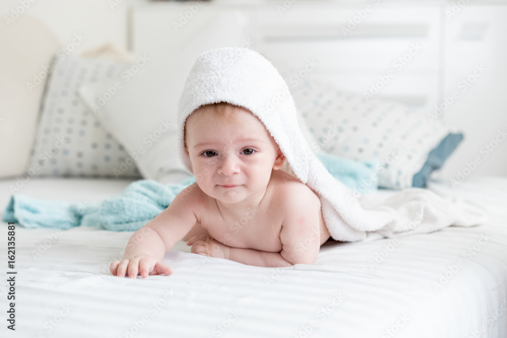 Baby boy in hooded towel crawling on bed after having bath Baby boy in hooded towel crawling on bed after having bath