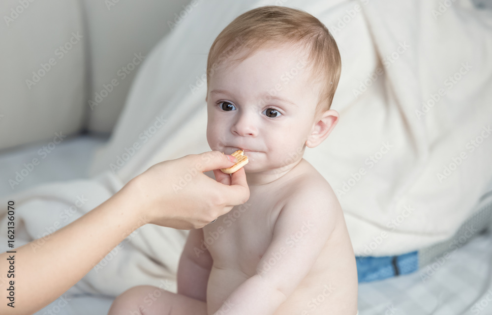 Mothers hand giving her baby son a biscuit Mothers hand giving her baby son a biscuit