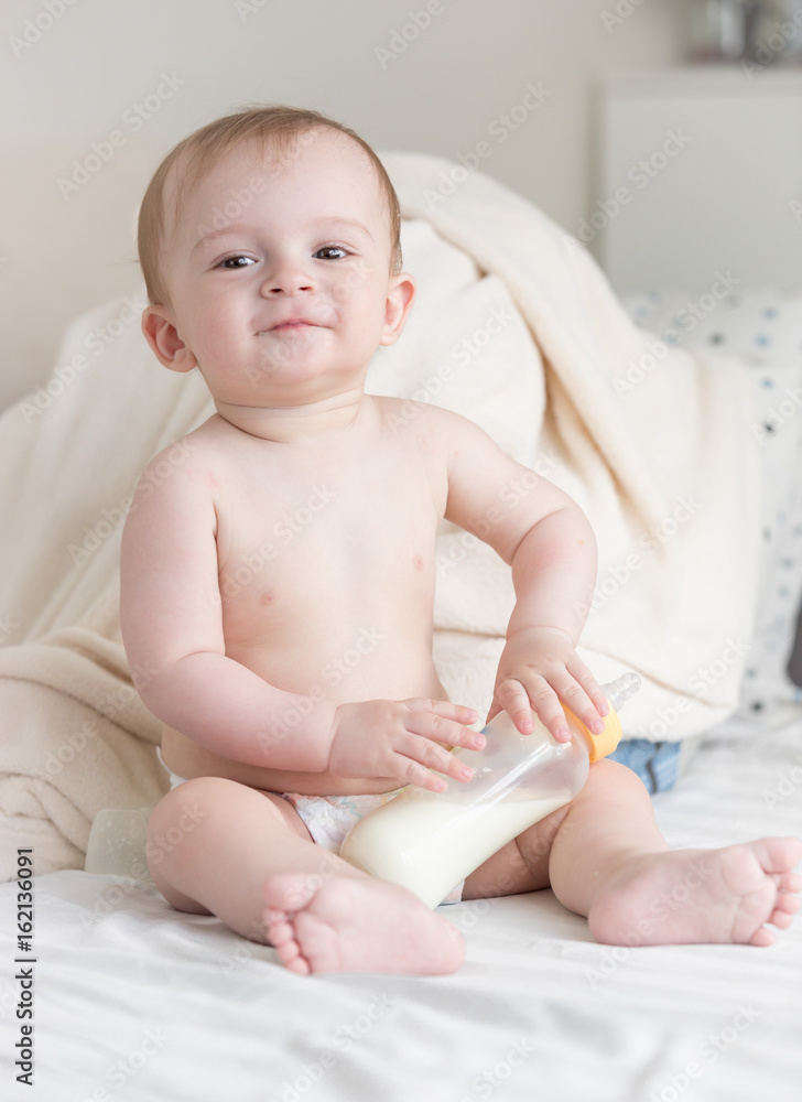 Beautiful cute baby in diapers sitting with milk bottle