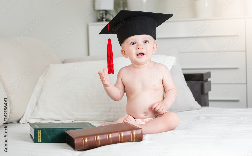Funny baby boy in diapers wearing black graduation cap Stock Foto Adobe Stock
