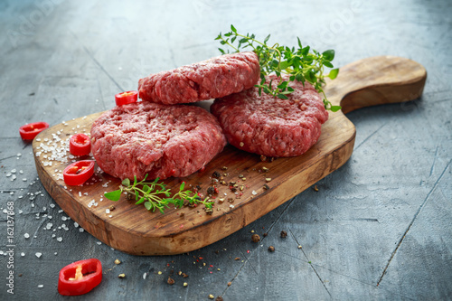 Home HandMade Raw Minced Beef steak burgers on wooden board. photo