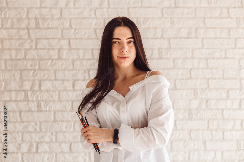 Cosmetologist with tassels for eyebrow correction posing on camera on white background.