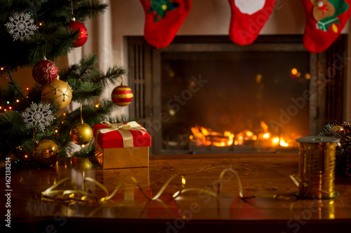 Christmas background with burning fireplace, Christmas tree, gift box and table © Кирилл Рыжов