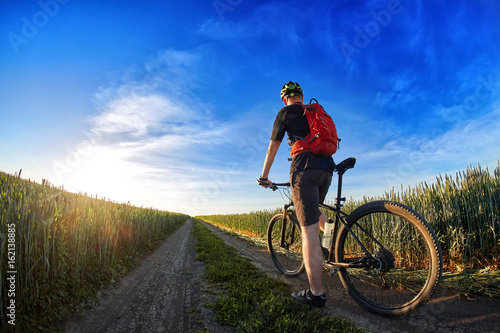 Rear view of the cyclist riding mountain bike on the trail against beautiful sky.