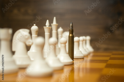 Conceptual photo of bullet in row of white pawns. Concept of conflict