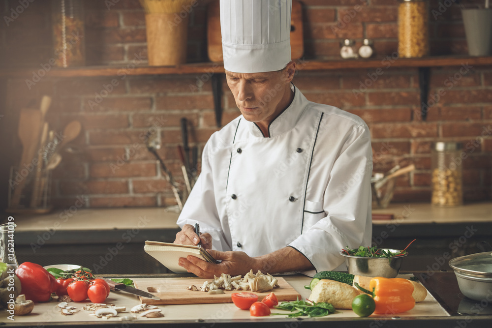 Mature man professional chef cooking meal indoors Mature man professional chef cooking meal indoors