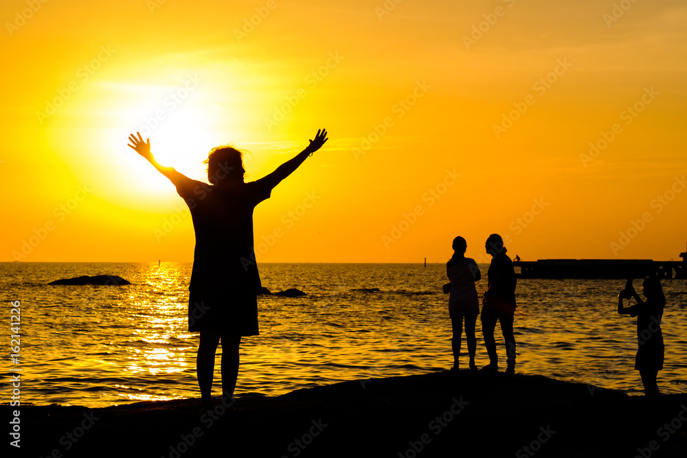 Fototapeta premium Girl teenager standing in the water with a raised hands at sunset