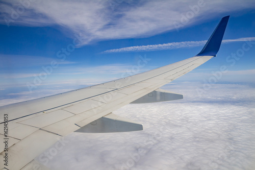 Airplane wing on the sky and over sea with clouds