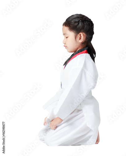 Asian little girl is sitting for concentration in taekwondo uniform isolated on white background with clipping path