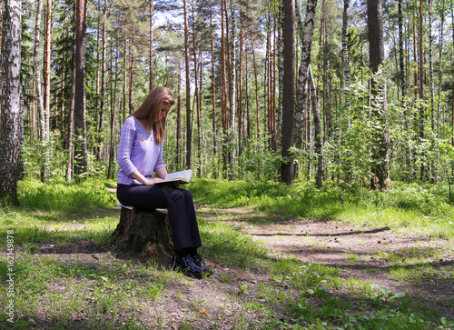 girl reading a book in the forest