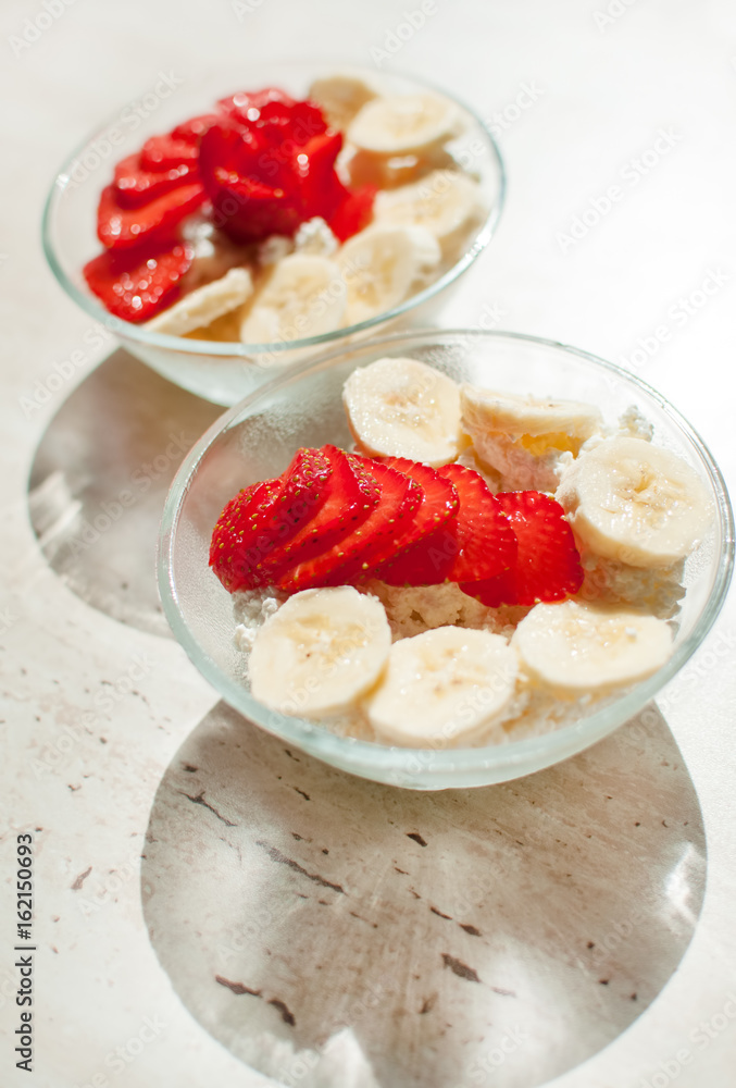 Two bowls of curd with strawberry and banana. Two bowls of curd with strawberry and banana.