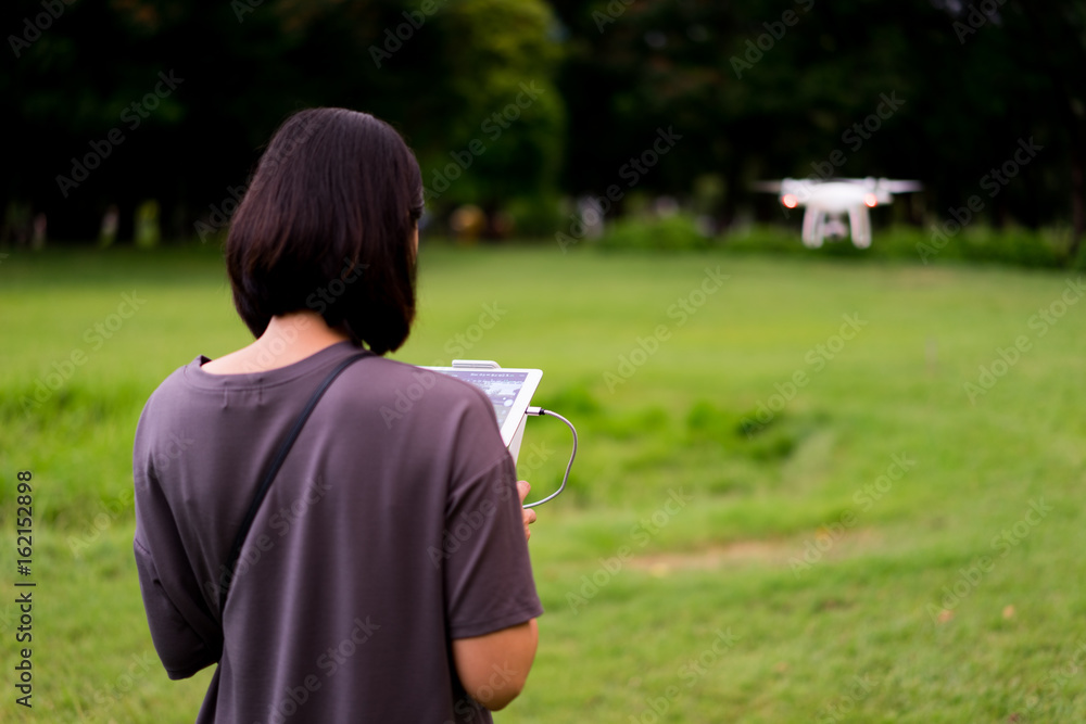 Women operating the drone by remote control in the park. Women operating the drone by remote control in the park.