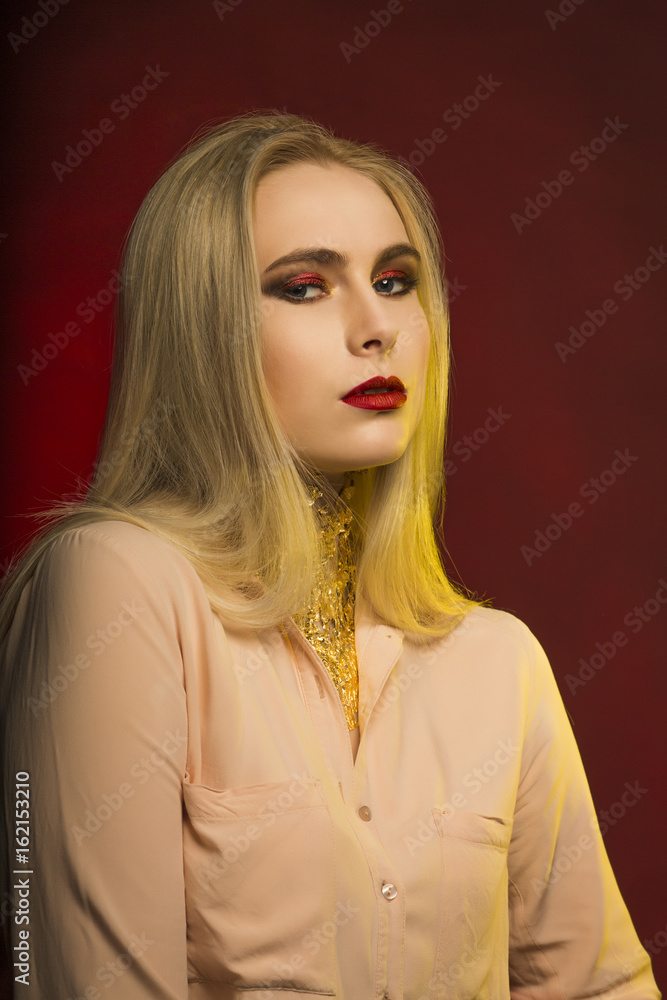 Sexy young lady with bright makeup and golden foil. Red and yellow studio light Sexy young lady with bright makeup and golden foil. Red and yellow studio light