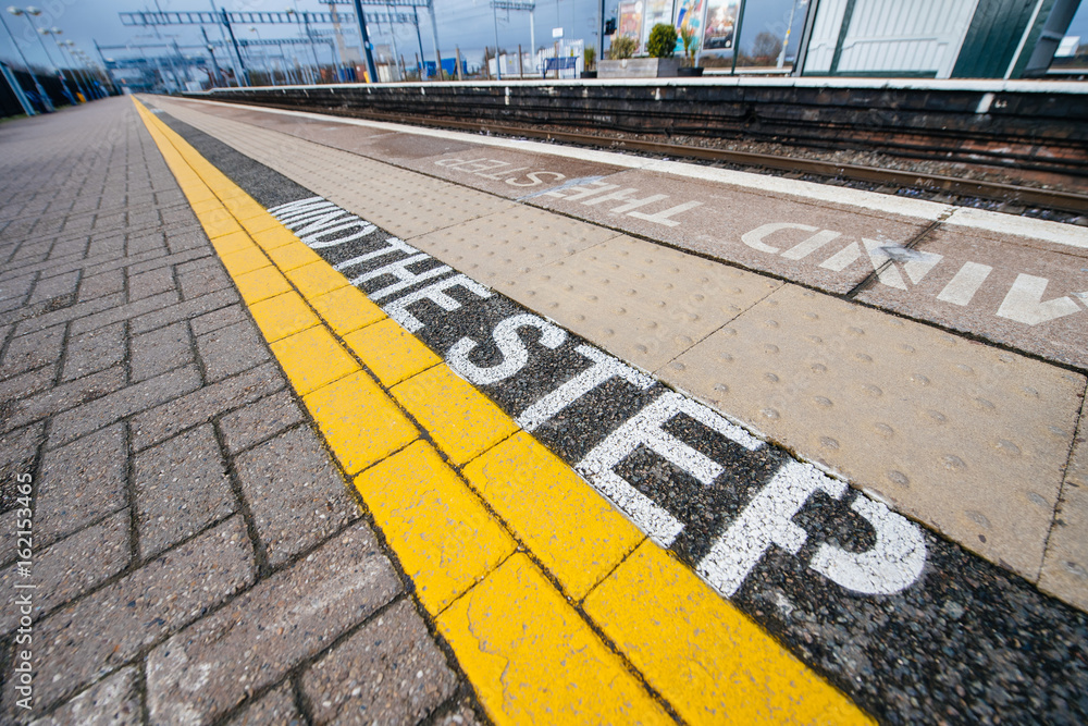 Fototapeta premium Mind the step yellow text line in British train station - visiting United kingdom taking care and security measures while traveling with train 