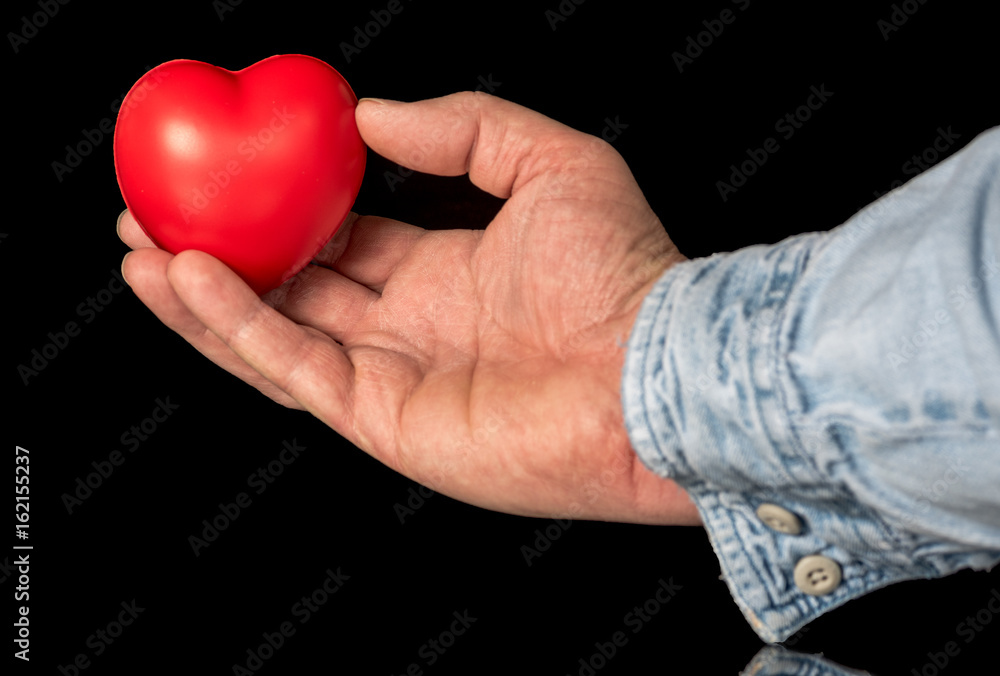 Fototapeta premium Hand holds a red heart on display