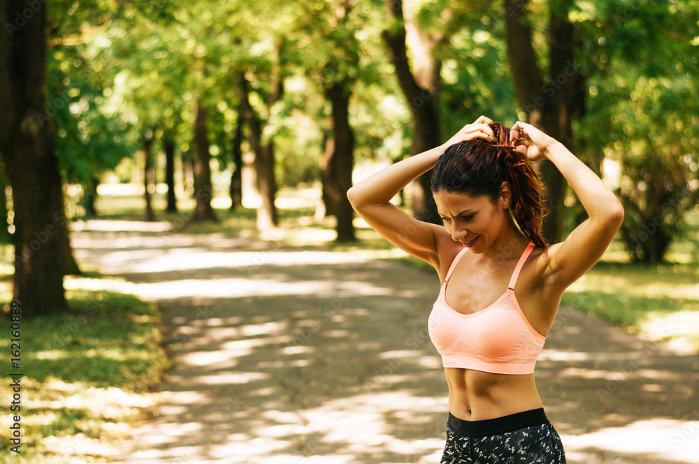 Woman tying hair in ponytail getting ready for run. Woman tying hair in ponytail getting ready for run.