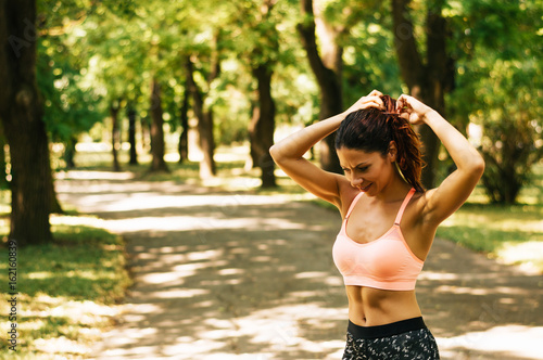 Woman tying hair in ponytail getting ready for run.