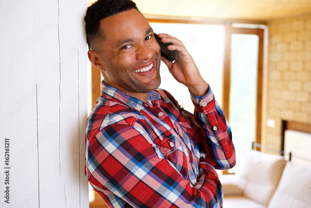 Close up smiling young african american man talking on smart phone at home