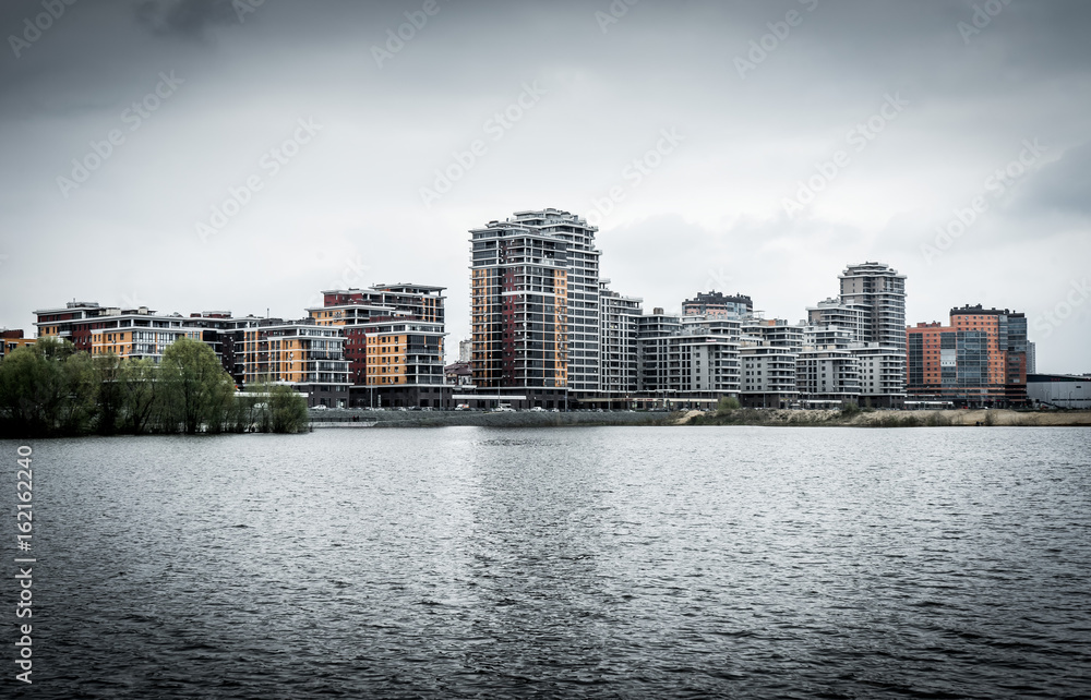Fototapeta premium Modern residential buildings on the banks of the river Kazanka. Urban High Contrast Desaturated Look. Cross processed photo